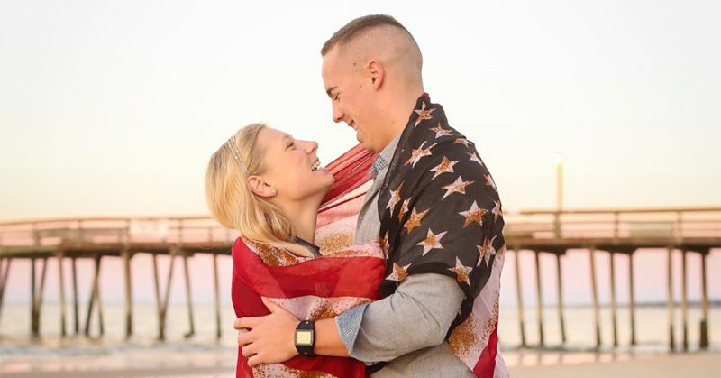 A military couple poses with the American flag