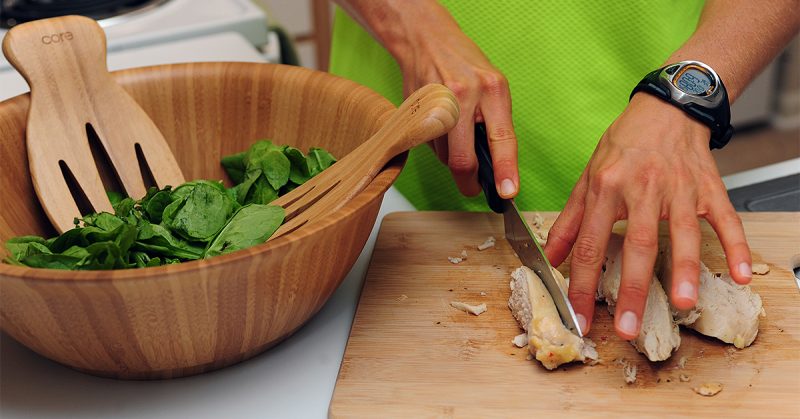 A person slicing chicken on a cutting board