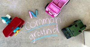 An aerial view of pavement with the words “Common Ground” written on it in sidewalk chalk.