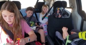 Four kids in the car on a road trip.