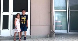 Two kids posing in front of a home.  