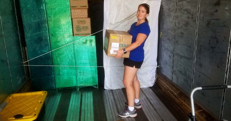 Lizann standing in a moving truck holding a box.