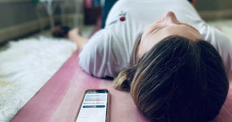 A woman using the Chill Drills app laying on a yoga mat