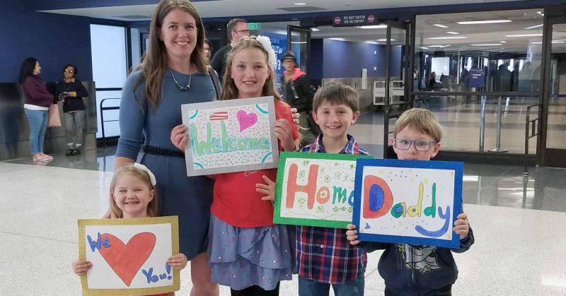 A family posing with signs at the airport