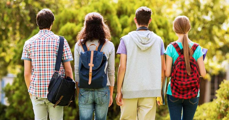 Four teenagers walking with backpacks on.