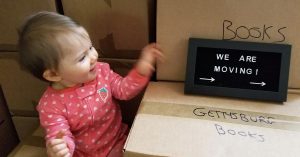 A baby sitting on moving boxes.