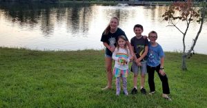 Lizann’s four children standing in front of a pond.