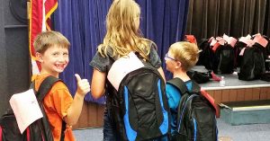 Lizann’s kids getting their new backpacks at a backpack giveaway event.