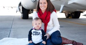 Kristi and her son posing outside of a military airplane