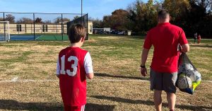 Kristi’s son walking on a soccer field, in his uniform, getting ready to play