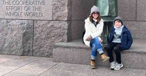 Kristi and her son sitting in front of an Eleanor Roosevelt monument