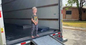 Little boy stepping out of the back of an empty U-Haul.