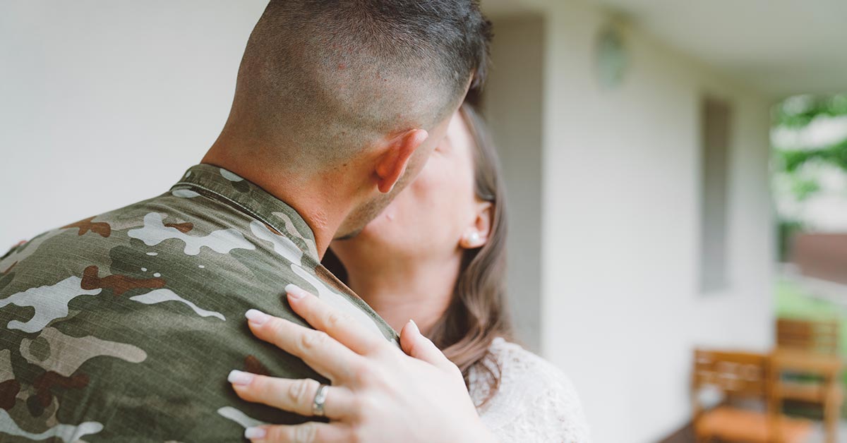 Two people kissing, the man is in military uniform.