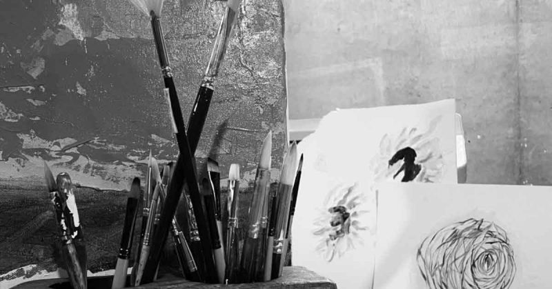 Black and white photo of paint brushes, paintings and drawings