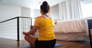 Woman sitting in her bedroom doing yoga