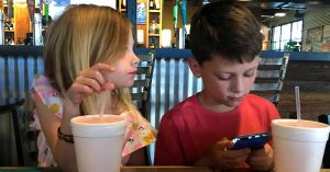 Kristi’s two kids using a phone while out to eat