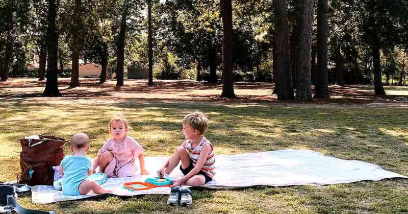 Kids in the backyard sitting on a picnic blanket
