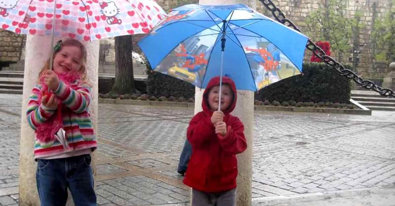 Lizann’s two kids using their umbrellas on a rainy day