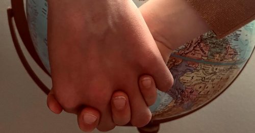 A couple holding hands in front of a globe