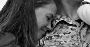 Wife with head on husband’s shoulder while smiling