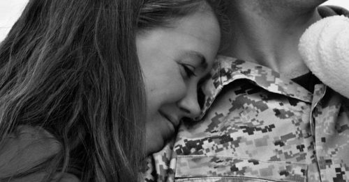 Wife with head on husband’s shoulder while smiling