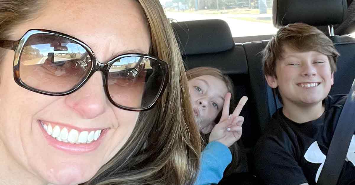 Woman and her two children smiling in car