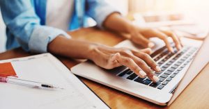 Hands typing on a laptop