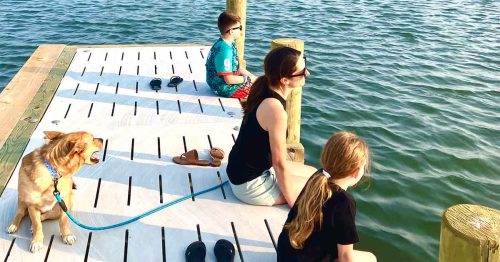 Kristi, her kids, and her dog sitting on a dock by the water