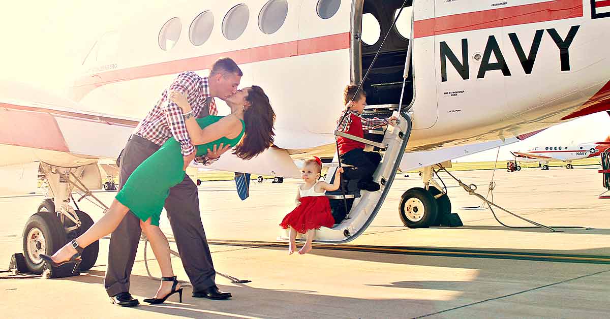 Kristi kissing her husband while her children sit on a plane’s steps