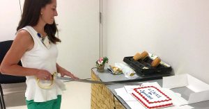Kristi cuts sheet cake using ceremonial sword.