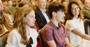 Kristi and her children sit at an indoor ceremony