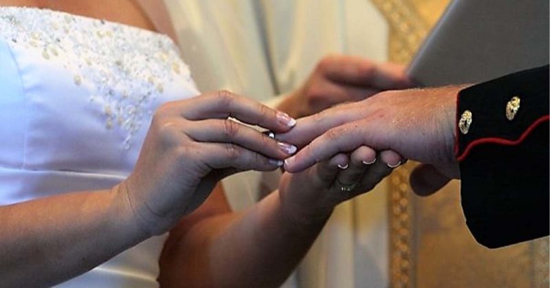 A close-up of a bride placing a ring on her partner’s finger during a wedding ceremony.