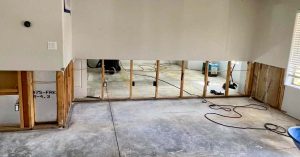 Interior of a partially renovated room with exposed wall studs, concrete floor and visible wiring