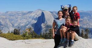 Lizann’s family poses on a rocky overlook with mountain peaks visible behind them