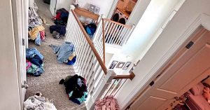 Upstairs hallway with piles of laundry scattered across the floor.