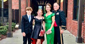 Kristi’s family dressed in formal attire posing together outside a brick building.