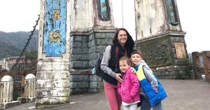 Kristi and her two children posing in front of a historic bridge during their travels.