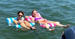Kristi and her daughter relaxing on inflatable floats in the water. 