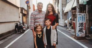Kristi and her family posing together on a city street during their travels. 