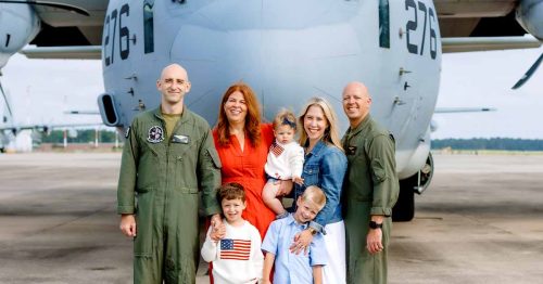 Lauren and her friend with their families posing in front of a military aircraft.