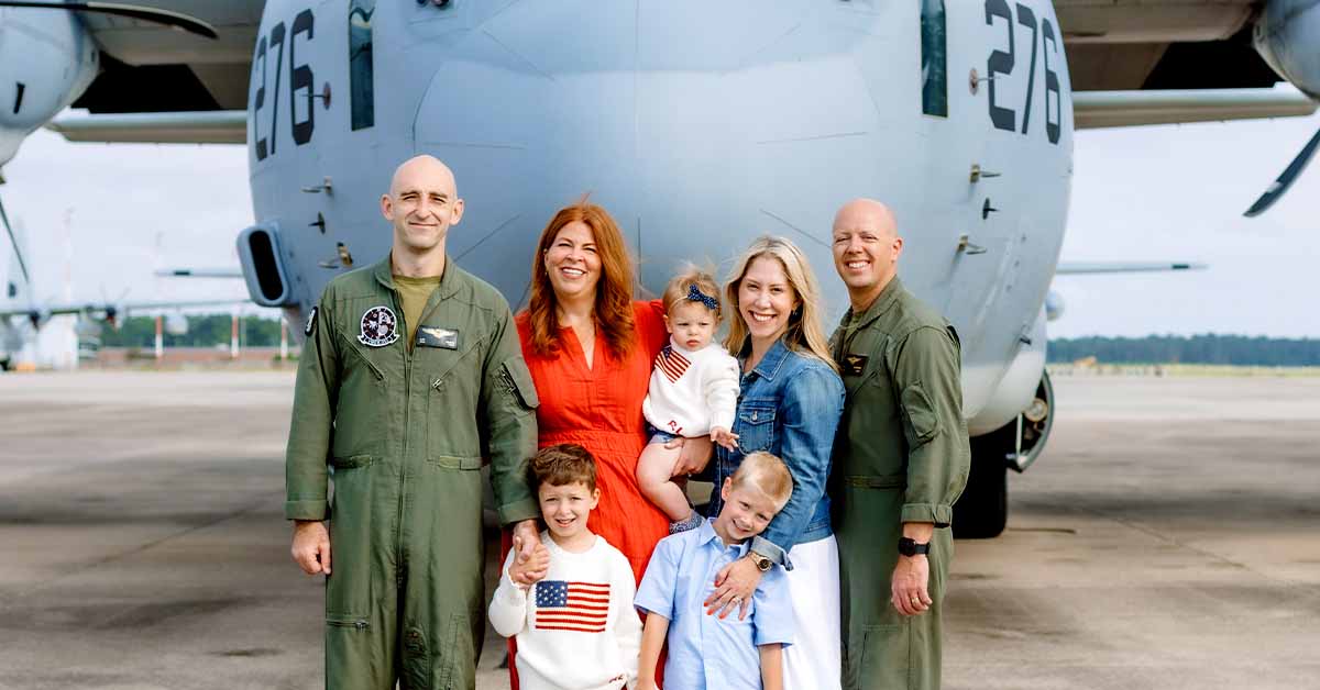 Lauren and her friend with their families posing in front of a military aircraft.