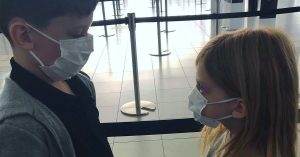 Two children wearing masks at the airport