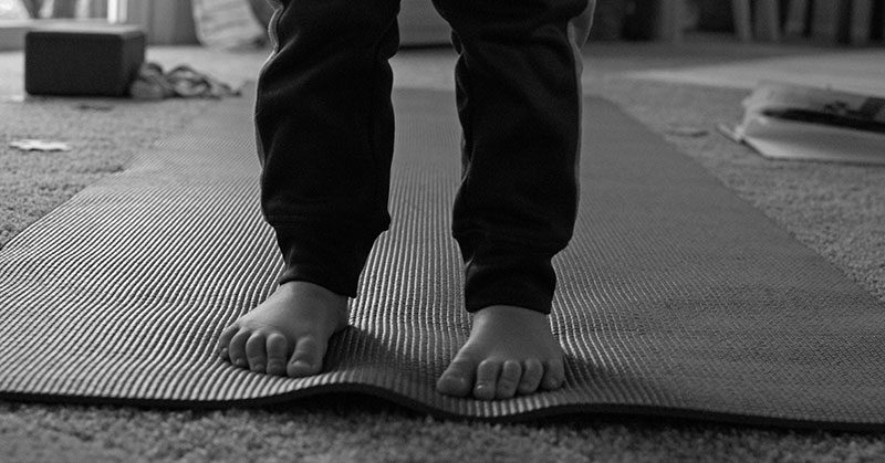 A closeup of a child's feet standing on a yoga mat