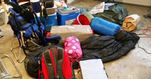An assortment of bags and camping supplies in a pile to be packed.