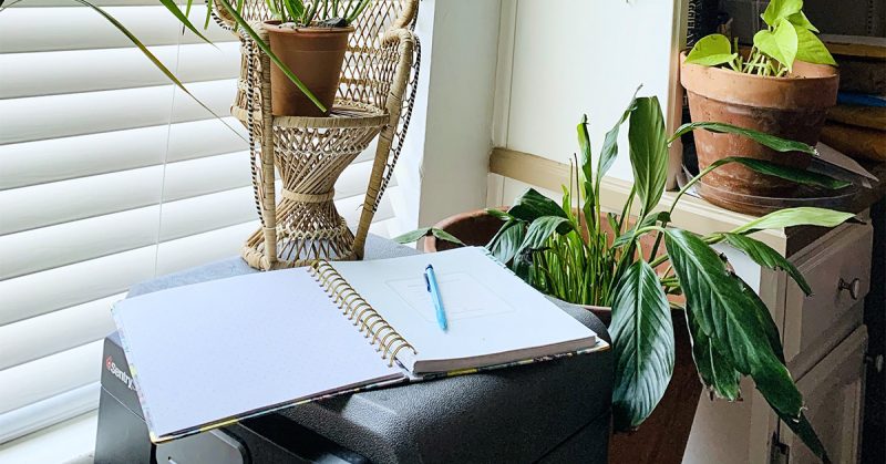 A notebook on a desk next to plants