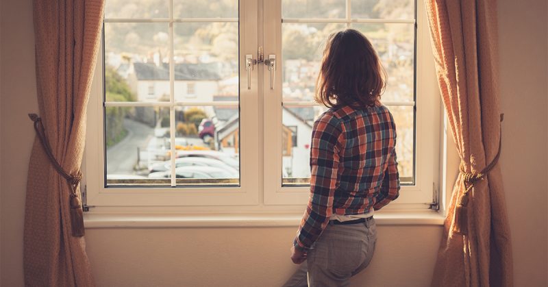 young woman standing and looking out a window