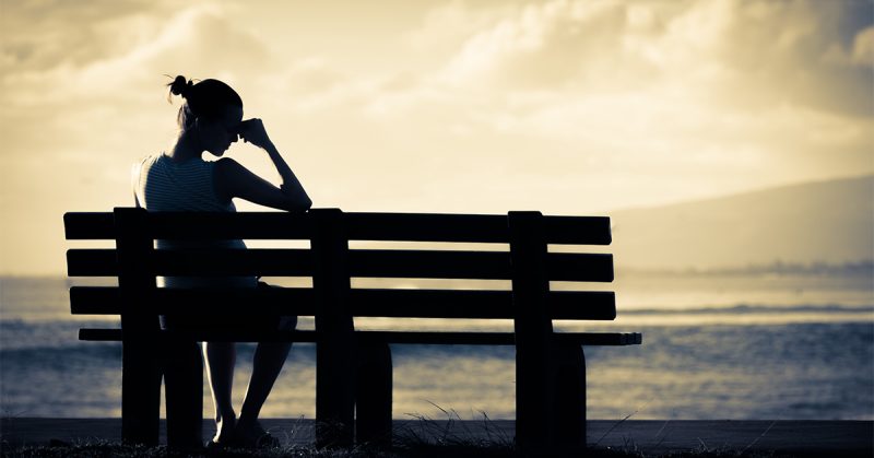 Lonely woman sitting alone on a bench