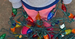 A closeup of a child wrapped up in chirstmas lights