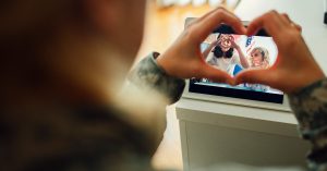 service member makes heart with fingers while facetiming