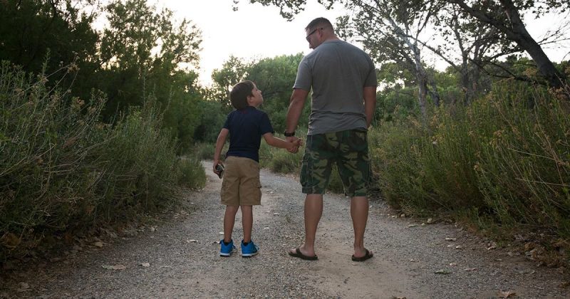 Father and son holding hands on a walking trail